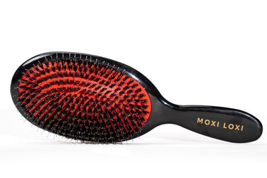 ScalpStim and Detangle Brush with red cushion, boar bristles, nylon pins, and gold MOXI LOXI handle mark.