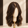 Moxi Loxi Sienna natural-texture silk-base topper in dimensional natural brown on an ivory mannequin with a gold stand