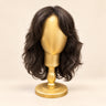 Soft curly dark brunette synthetic sample wig shown from the front on a gold display stand.